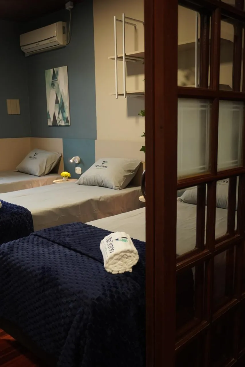 Quarto com duas camas, cobertores azul-marinho e porta de madeira com vidro