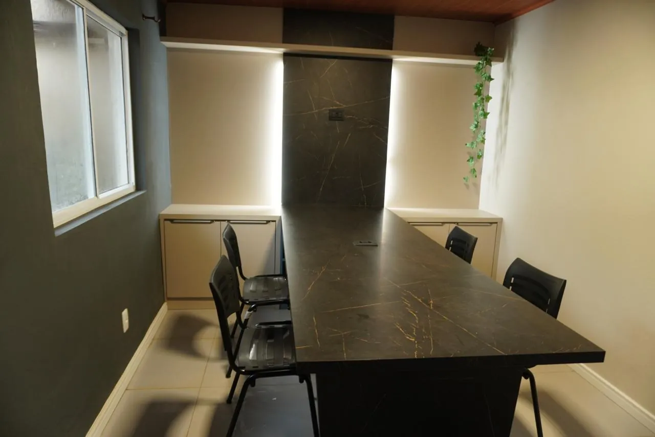 Sala de reunião com mesa escura e cadeiras